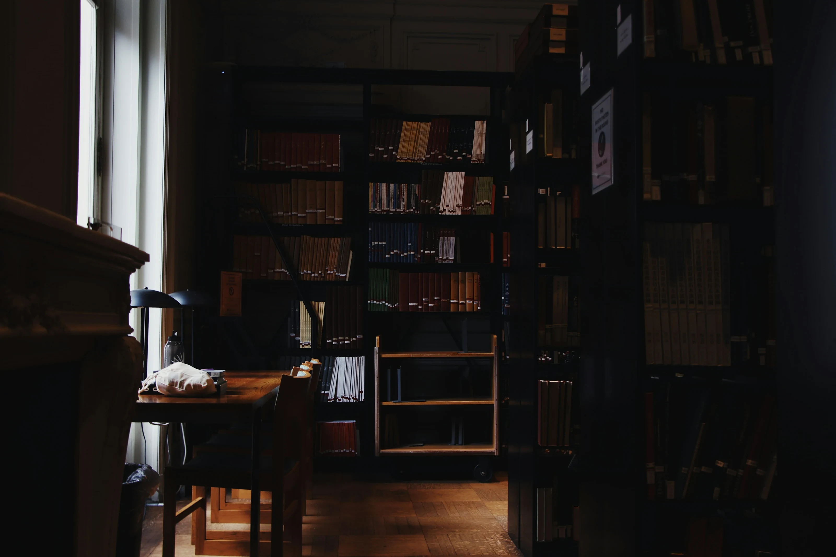 Biblioteca jurídica com estantes de livros em penumbra